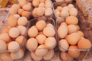 Fresh farm eggs displayed in transparent containers at a local market