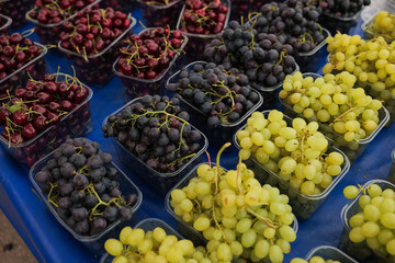 Freshly harvested grapes and cherries displayed at a market in the late afternoon