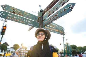 Woman Standing by Directional Signpost in Yogyakarta City During Daytime