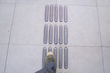 Person Standing on Tactile Paving with Textured Tile Pattern in Urban Space