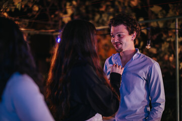 A group of friends socializing at an outdoor evening event under string lights, capturing intimacy...