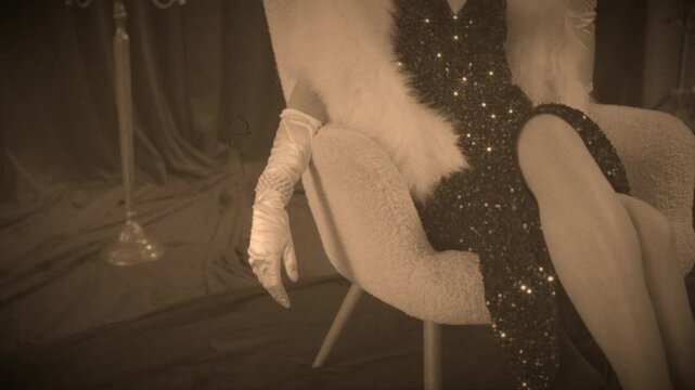 film sepia color, beauty queen Retro lady sexy woman fashion model sitting on chair old roar style white fox faux fur boa cape shiny dress long lrgs. Glamour girl clothing evening gown high gloves