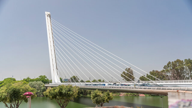 Alamillo Bridge with tall pylon and steel cables crossing over Guadalquivir River timelapse hyperlapse in Seville, Spain