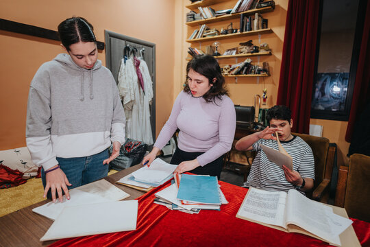 A group of young actors working together backstage in a theater setting, discussing and studying documents related to their performance.