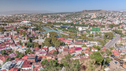 Fototapeta premium Colorful traditional houses with wooden balconies and red roofs in the Old Town of Tbilisi aerial timelapse, Georgia.