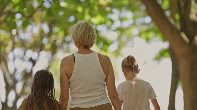 Mother walking with children in a sunny park