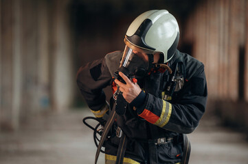 Standing in the abandoned building. Firefighter in professional equipment is indoors