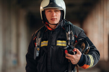 Firefighter in professional equipment is indoors in abandoned building