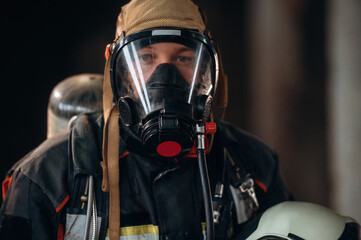 Front view, in the mask. Firefighter in professional equipment is indoors in abandoned building
