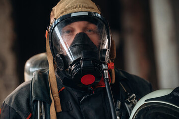 By the help of air mask. Firefighter in professional equipment is indoors in abandoned building