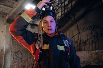 Against old stairs. Firefighter in professional equipment is indoors in abandoned building