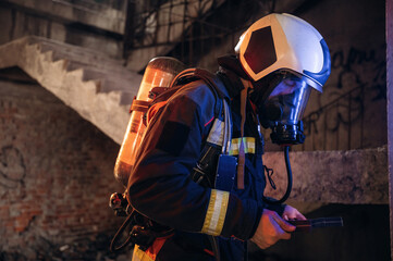 View from the side, with air balloons and mask. Firefighter in professional equipment is indoors in...