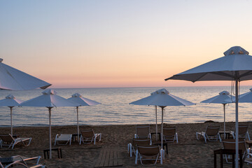 Sunset over beach umbrellas and loungers at Arillas Beach in Corfu, Greece