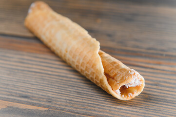 Delicious wafer rolls with boiled condensed milk on a wooden background