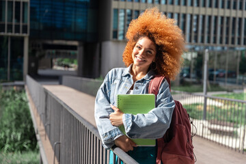  Young latin student woman holding educational worksheets, ready to studying. Smiling portrait of...