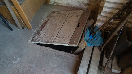 The entrance to the basement. Hinged wooden cover to the basement