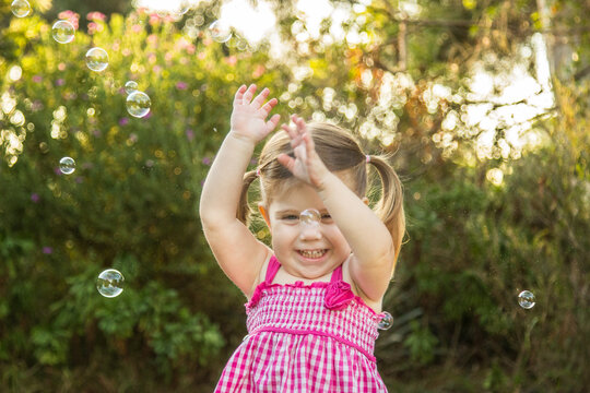 Young girl chasing bubbles outside