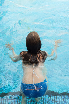 girl swimming in pool, from behind