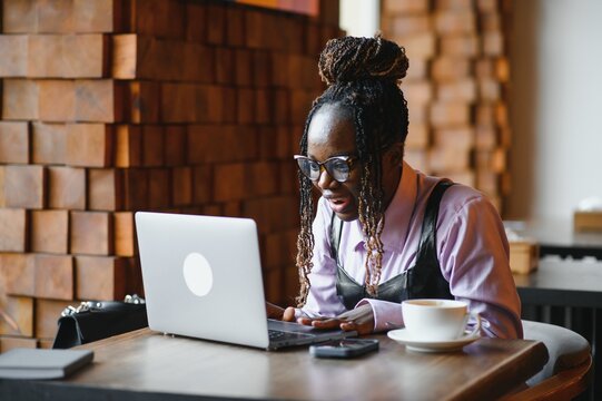 Portrait of an african american young woman sitting at cafe with laptop writing her blog