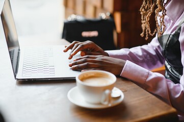 Portrait of smart young woman with mobile phone working on laptop at outdoor coffee shop
