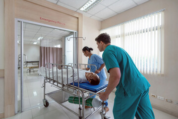 Two healthcare worker are hurriedly transferring a patient on a stretcher in a bright hospital...