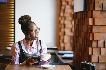 Smiling woman using smart phone in a modern cafe