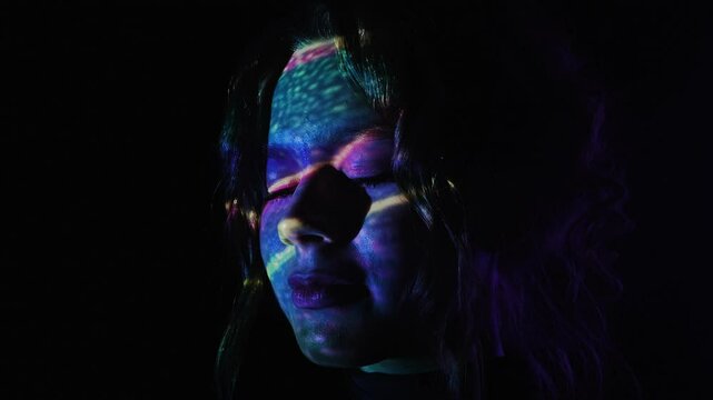 Colorful light reflections on a woman face in dark background