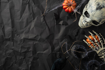 Halloween setup with a skull, skeleton hand, and pumpkins on a textured dark background