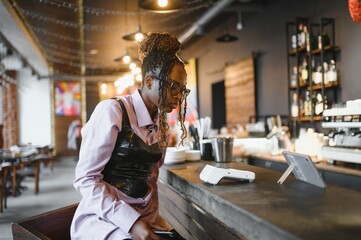 African woman paying by phone in a cafe.