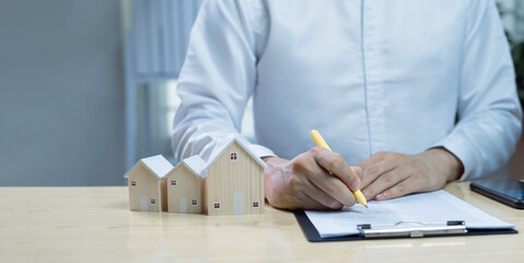 House model with businessman signing purchase or mortgage contract. Concept of real estate...