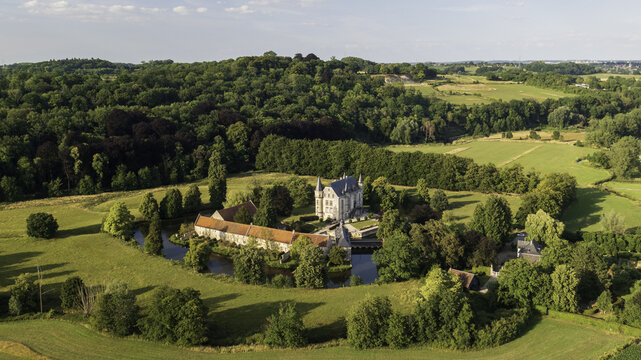 Aerial view of a grand castle nestled within lush greenery, surrounded by serene waters and vibrant landscapes, Schin op Geul, Limburg, Netherlands.