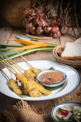 satay skewers with grilled pork and dipping sauces served on banana leaf plate