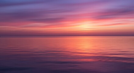 Obraz premium Calm ocean reflecting a vibrant sunset with pink and purple sky colors above