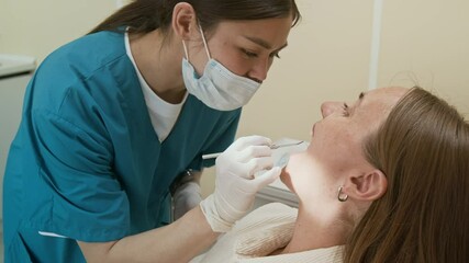 Side view closeup of young female dentist examining patient in dental clinic and using mirror, copy space