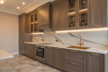 A modern kitchen with gray cabinets marble countertops and gold fixtures in a well lit room