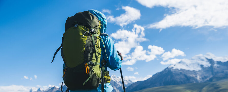 Backpacking woman hiking on flowering grassland mountain top
