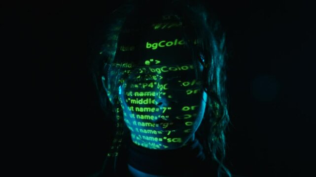 Portrait of a woman with green digital code projection on her face.