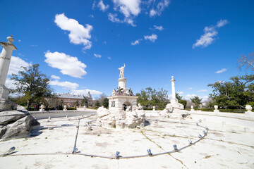 Fototapeta premium Fountain in Aranjuez, Spain surrounded by clear skies and historical architecture during a sunny afternoon