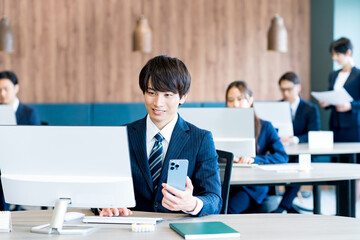 オフィスでスマホを持つビジネスマン