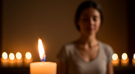 A soft-focus candle flame in the foreground with blurred meditating figure in the back, captured with depth and ambient indoor lighting. Tone: warm and intimate, mood: spiritual quiet.

