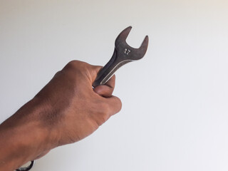 A man's hand holding a ring spanner, isolated on a white background, also known as a combination wrench.