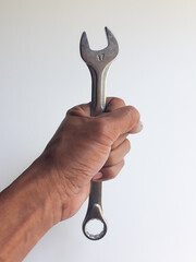 A man's hand holding a ring spanner, isolated on a white background, also known as a combination wrench.