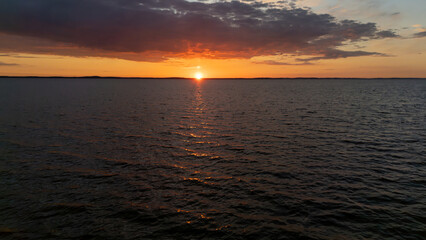 A vibrant sunset casts warm colors on the water as the day transitions to night.