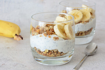 Healthy Breakfast Parfait with chia seeds and Granola and Sliced Bananas in drinking glass