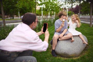Snapshot and sweets. Grandma takes a phone photo of the grandkids eating ice cream. Concept of joy...