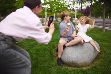 Snapshot and sweets. Grandmother taking picture of kids with ice cream outdoors. Concept of family photo tradition, joy capture, grandparent love, outdoor memory.