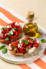 Bruschetta with creamy burrata cheese, fresh tomatoes, balsamic vinegar glaze and fresh basil leaves. Italian summer appetizer. Olive oil bottle. Vertical image.