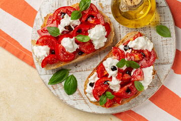 Top view of Bruschetta with creamy burrata cheese, fresh tomatoes, balsamic vinegar glaze and basil leaves. Italian summer appetizer. Olive oil glass bottle.