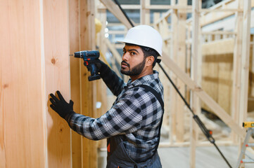 Construction of modular houses. Male indian construction worker in uniform and hard hat at...