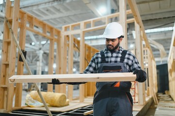 Modern modular house. Indian worker works on the construction of a wooden house